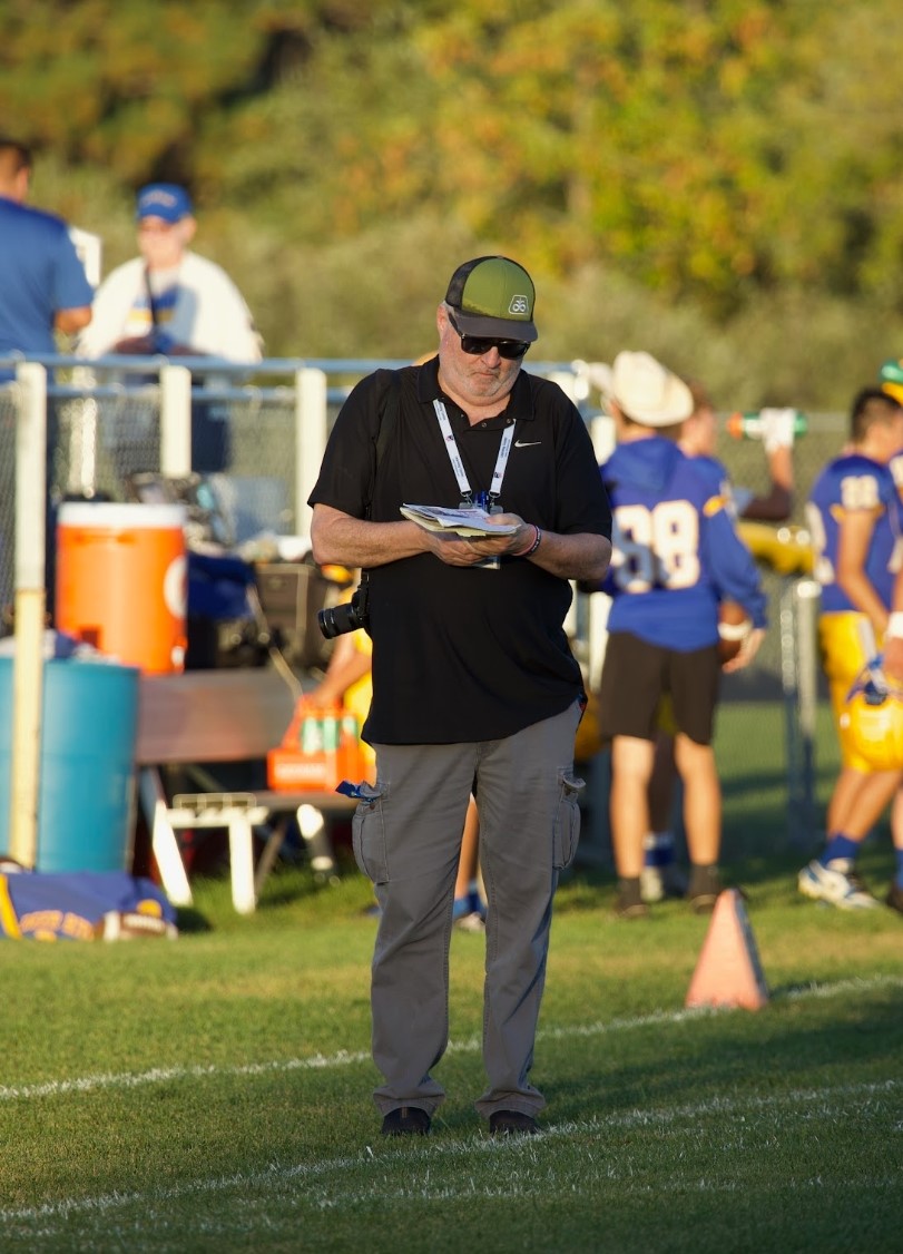 John Millea walks the sideline during a high school football game.