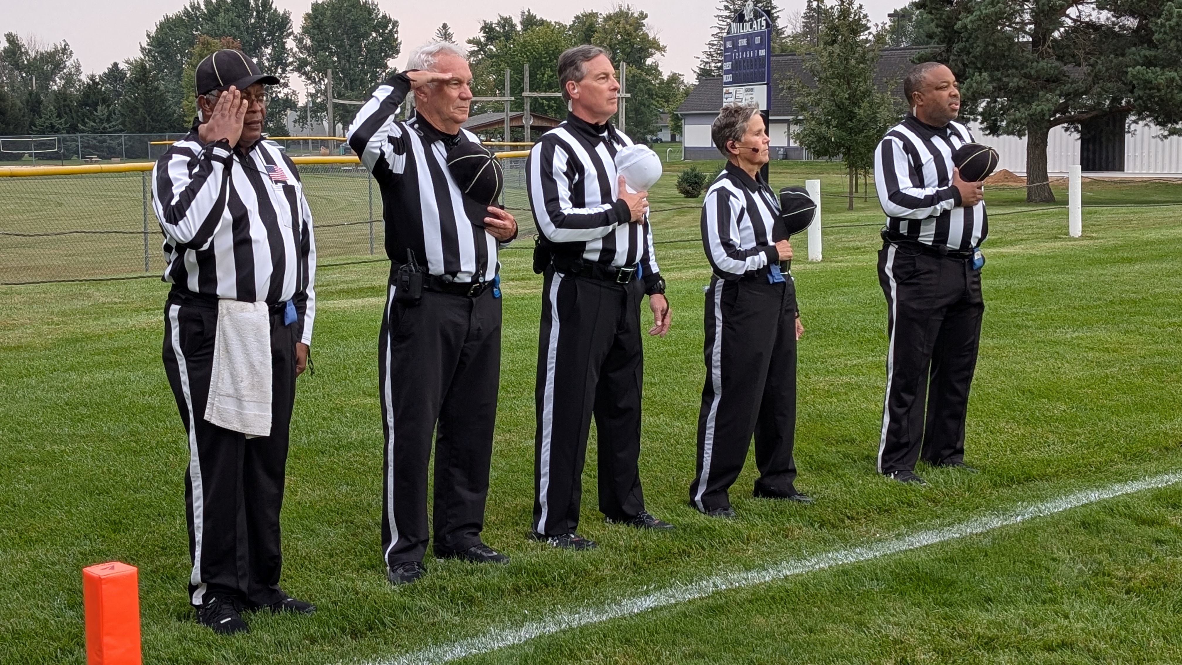 Officials stand for the national anthem before a high school football game.