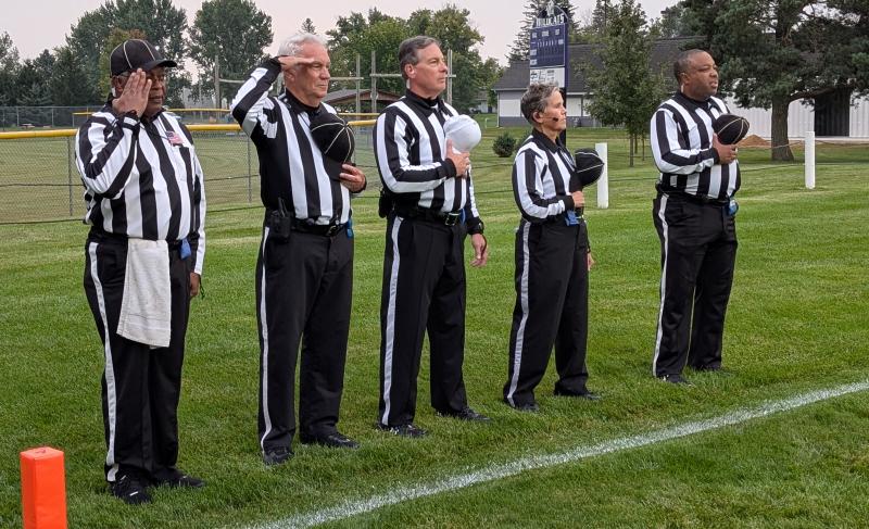 Officials stand for the national anthem before a high school football game.