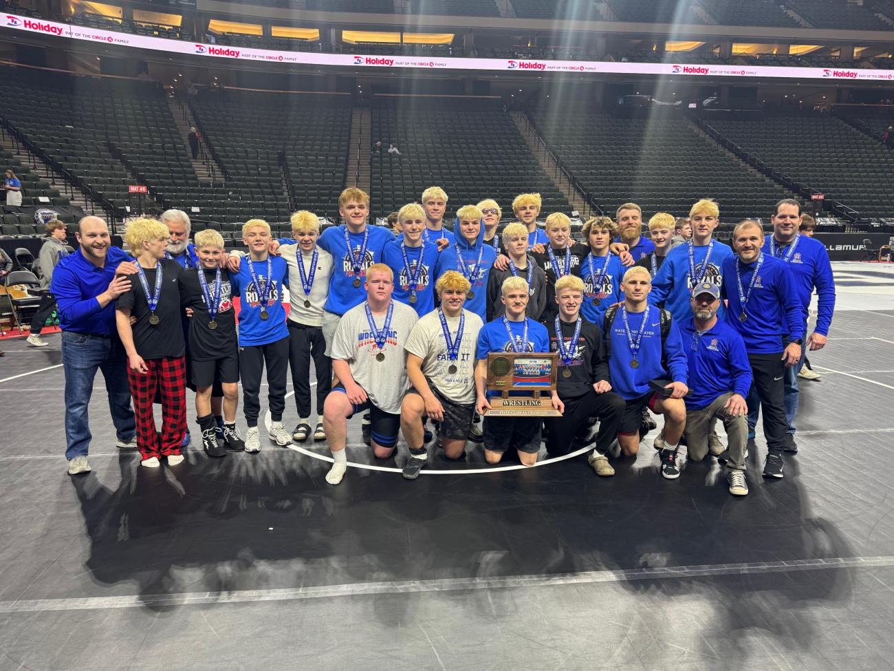 The 2025 Watertown-Mayer Wrestling team poses with its 2025 state championship trophy.