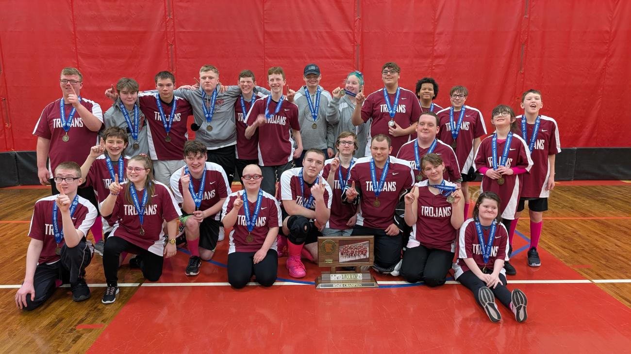 The New Prague Adapted Floor Hockey CI team poses with its state championship trophy.