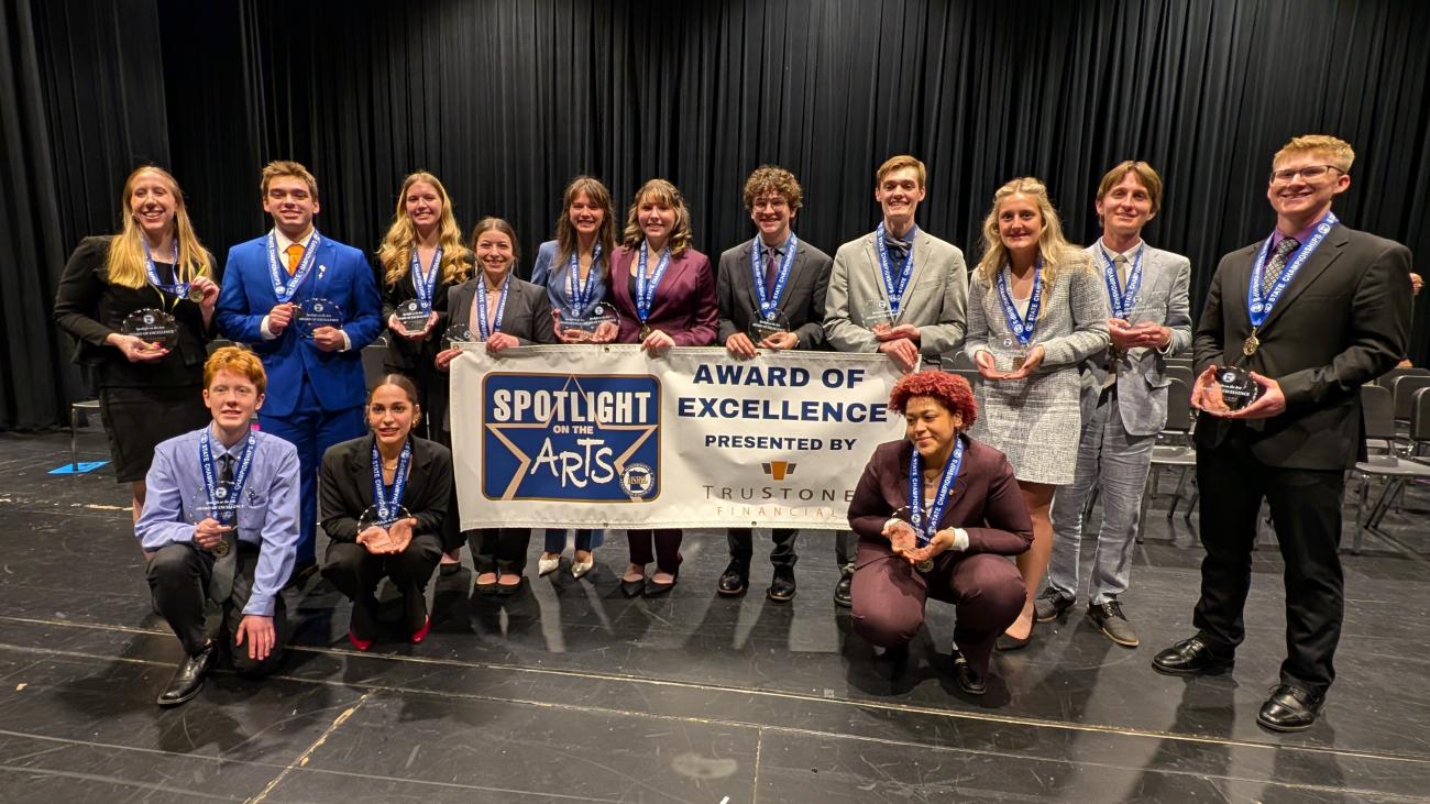 The Class A Speech state champions hold a Spotlight on the Arts banner.