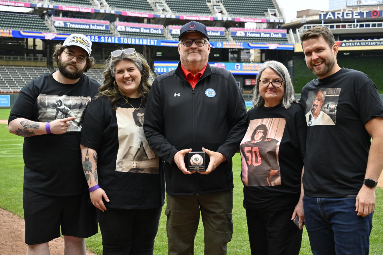 John Millea is surrounded by family members as he holds a commemorative baseball at Target Field during a Baseball State Tournament pregame ceremony honoring his MSHSL career.