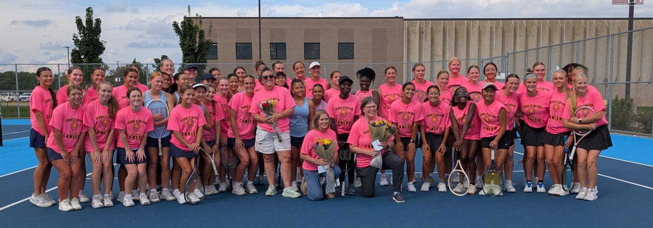 The Coon Rapids and Blaine Girls Tennis teams and their distinguished guests wearing pink Serve It Up For Cancer T-shirts