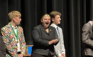 Darby Frei reacts on stage during a Speech Section Tournament awards ceremony.

