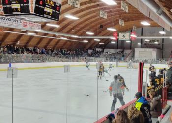 An overview of Roseau Memorial Arena featuring fans watching a high school hockey game.