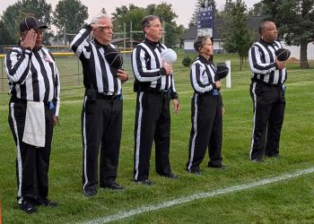 Officials stand for the national anthem before a high school football game.